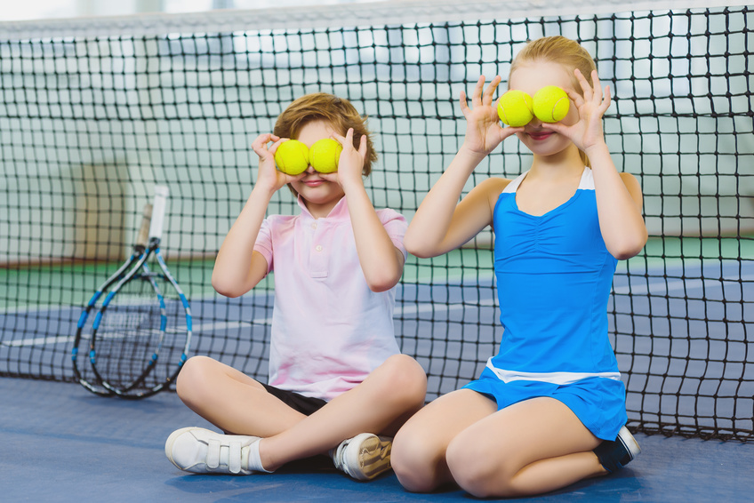 Two children holding choices from our best tennis balls guide over their eyes