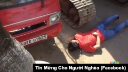Một người dân lấy thân mình chặn xe ủi đến cưỡng chế phá nhà ở vườn rau Lộc Hưng.