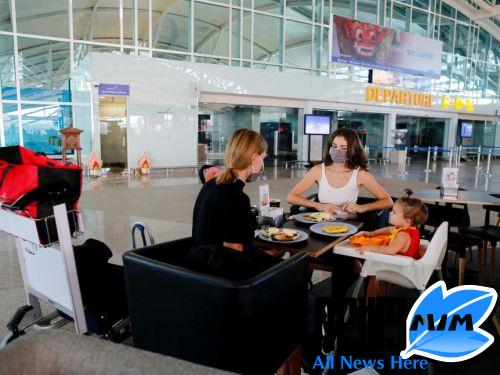Two women and a baby wait for a flight as they sit at a cafe at a near-empty airport in Bali.