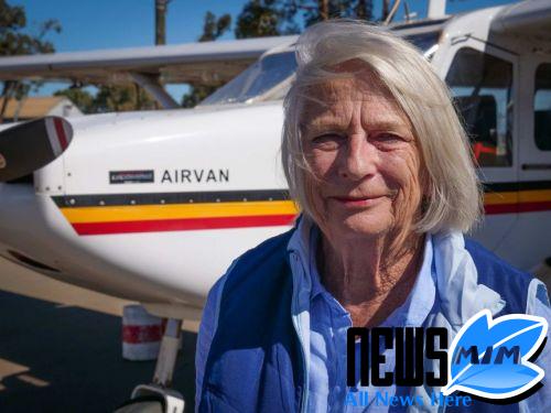 Older woman in blue shirt stands in front of small aircraft called Airvan