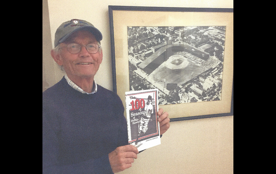 Jim Overfield, with the oversized, framed photo of Offermann Stadium that once hung over his father’s mantel and is now in his office in Vermont.