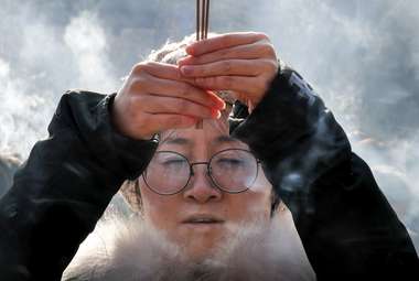 A woman holding incense sticks offers prayers on the first day of the new year at Yonghe Temple, in Beijing. (AP Photo/Andy Wong)