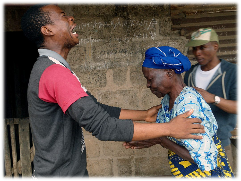 A young man praying for a old woman during NCCF Rural Rugged