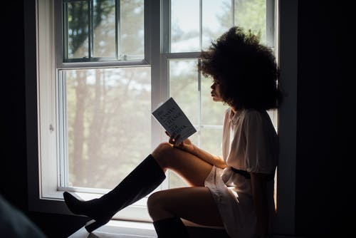 Free Woman Sitting On Window Reading Book Stock Photo
