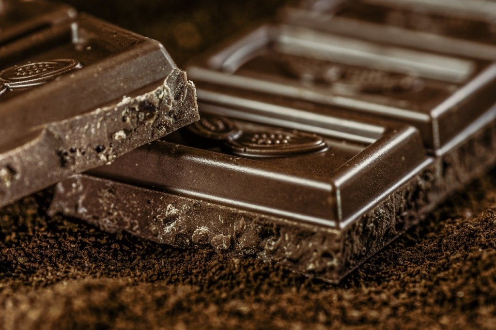 Pieces from a bar of dark chocolate on a dark brown background