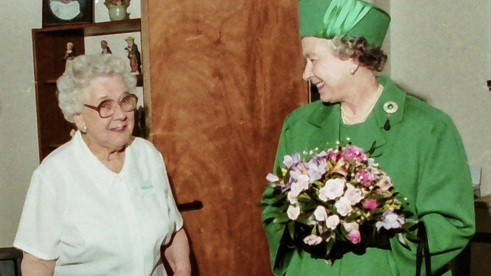The Queen meets a woman in a flat