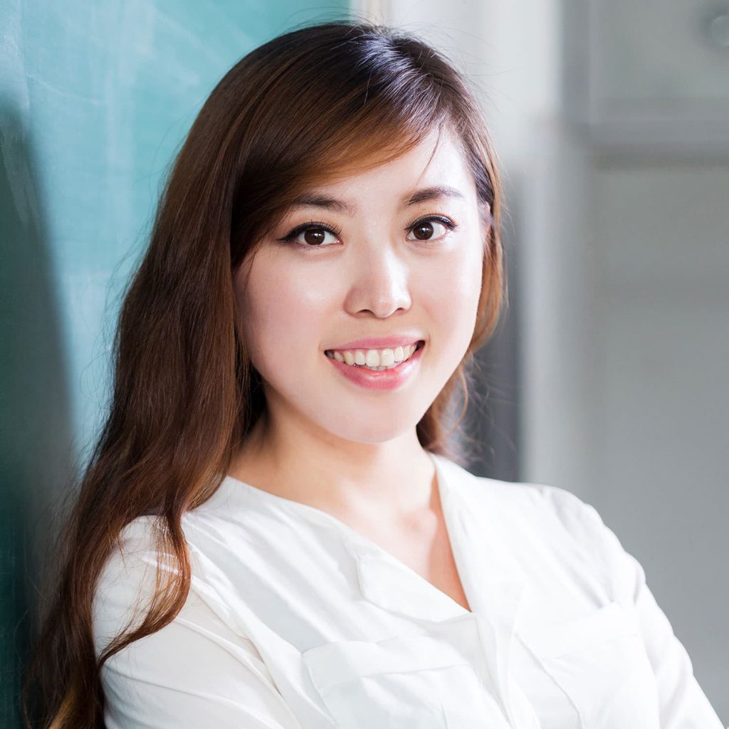 Young woman leaning against classroom chalkboard