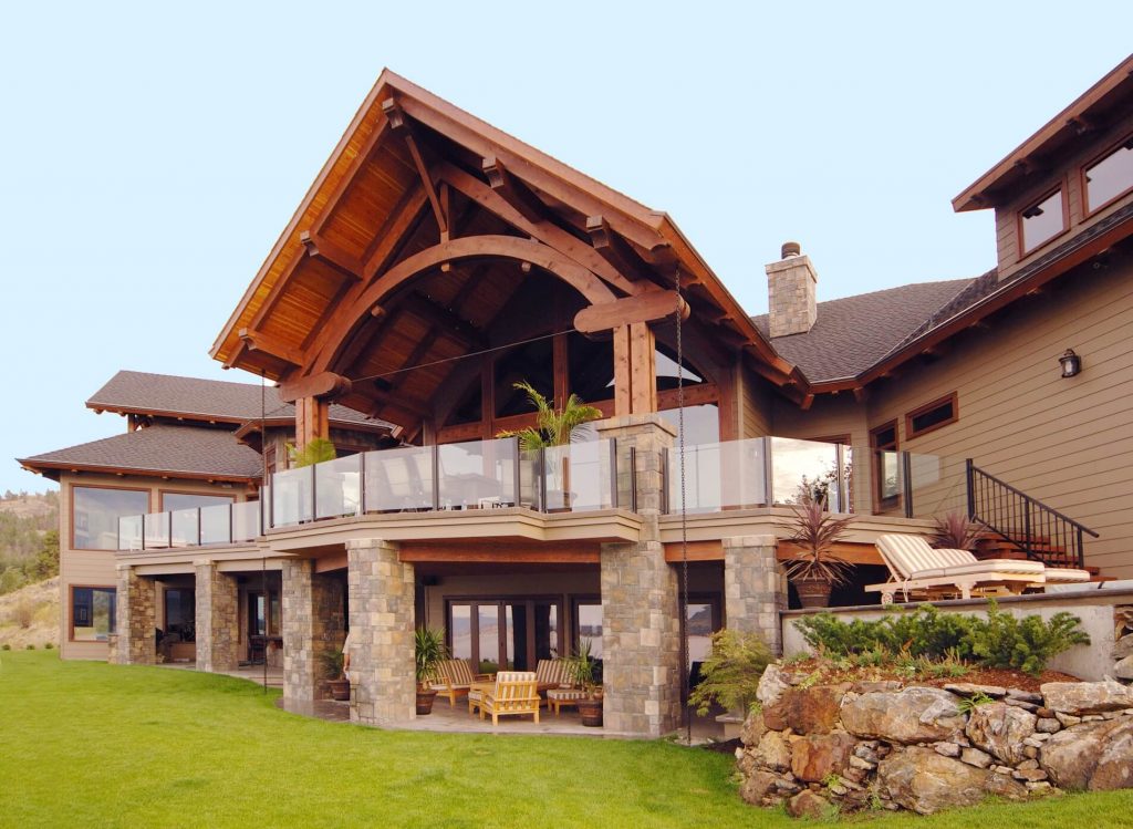 A large timber house with a balcony and a covered patio
