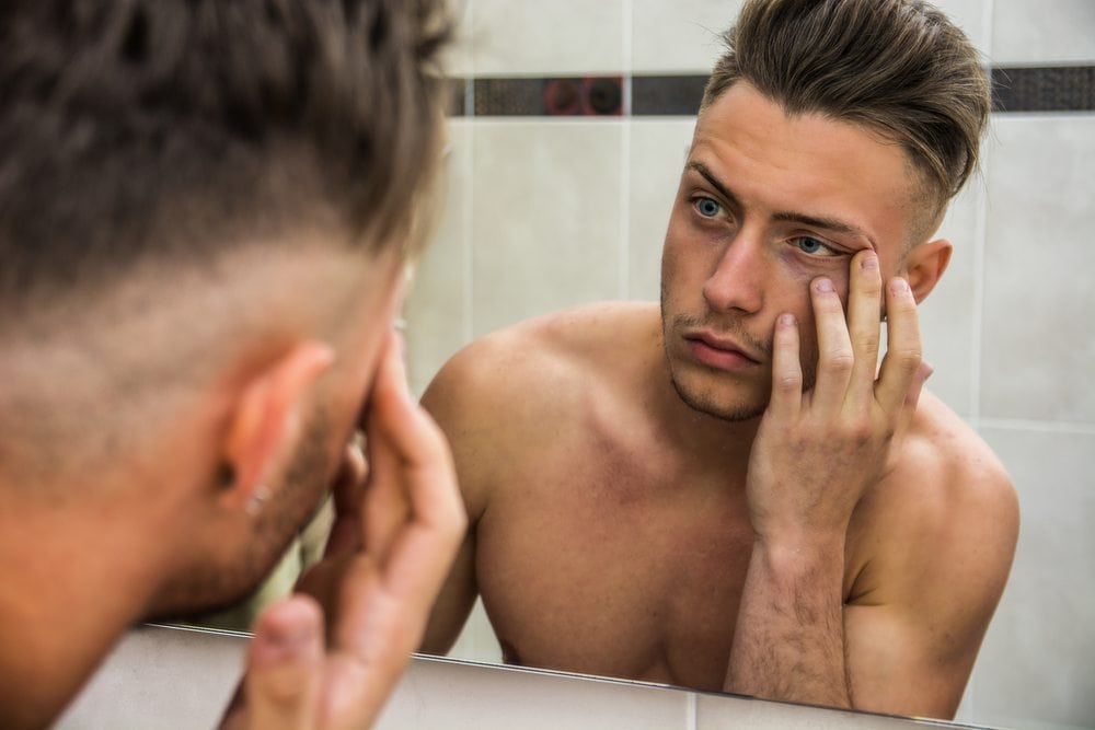 man looking at his facial skin in mirror
