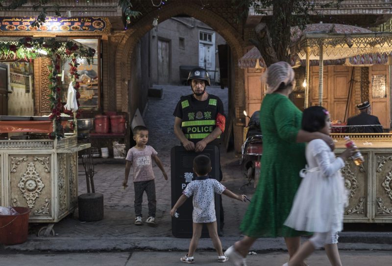 Uighur children joke as they taunt a local police officer in Xinjiang