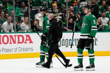 Dallas Stars' Tyler Seguin, left, is escorted off the ice by a staff member and Nils Lundkvist, ...